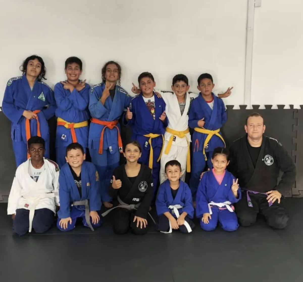 Turma infantil de kimono azul com faixas amarela, laranja e cinza